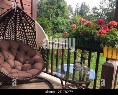 Schaukel und Blumen auf einem schönen gemütlichen Balkon. Stockfoto