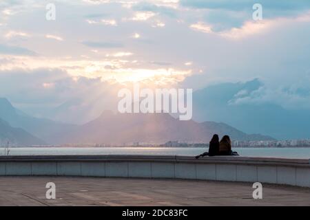 Antalya, Türkei - 22. Februar 2019: Menschen sitzen auf der Steinbrüstungsanlage auf dem Platz der Altstadt Kaleici in Antalya. Stockfoto