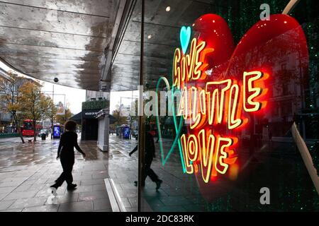 London, Großbritannien, 19. November 2020: Trotz Englands Lockdown und regnerischem Wetter gehen manche Leute zum Schaufensterbummeln oder benutzen Click and Collect im Londoner West End. Ein Neonschild im Fenster von John Lewis fordert die Menschen auf, "ein wenig Liebe zu geben". Anna Watson/Alamy Live News Stockfoto