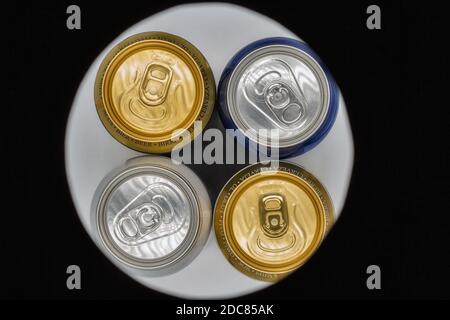 Verschiedene geschlossene Biertrinkdosen Nahaufnahme von oben durch Kreisloch in schwarz Stockfoto