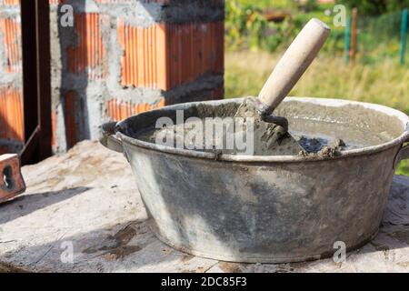 Kelle im Mörtel, ein Behälter aus Zement, Baukonzept Stockfoto