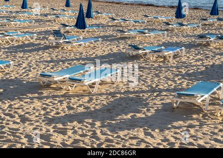Leerer Strand mit Liegestühlen und Sonnenschirmen in Benidorm, Spanien.Reise- und Urlaubskonzept.Sommerparadies Resort Hintergrund. Stockfoto