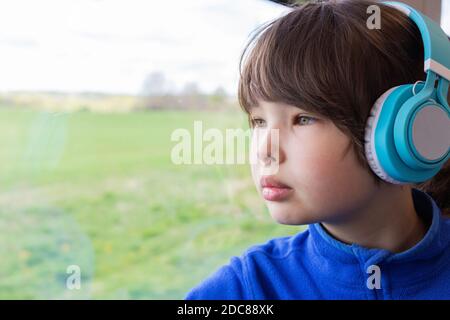 Das Mädchen schaut aus dem Fenster des Zuges und hört Musik in Kopfhörern. Stockfoto
