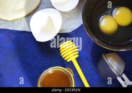 Verschiedene Zutaten für das winterliche Backen und andere Rezepte, Honig, Äpfel, Kräuter und Gewürze auf dunkelblauem Hintergrund. Draufsicht. Stockfoto