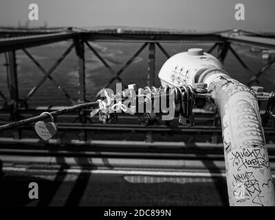 Liebe Vorhängeschlösser und Graffiti auf der Brooklyn Bridge, New York, mit dem Hudson River und New Jersey im Hintergrund Stockfoto