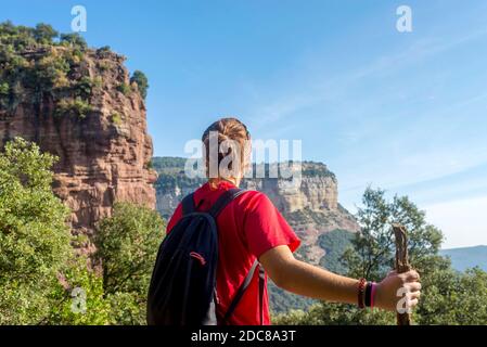 Rückansicht einer jungen Frau, die auf einem hohen Berg steht Halten Sie einen Stock Stockfoto