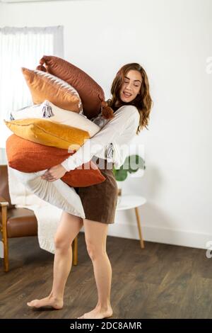 Frau hält Stapel von Kissen und geht Stockfoto