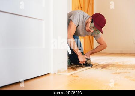 Mittlerer Erwachsener Mann installiert Hartholzboden zu Hause Stockfoto