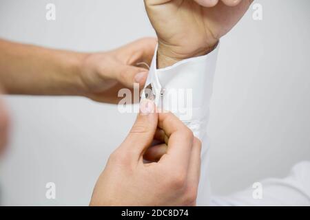 Ein Bräutigam, der sich für die Hochzeitszeremonie vorbereitet und Manschettenknöpfe aufsetzt Stockfoto