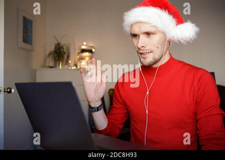 Ein Videoanruf auf dem Weihnachtscomputer im Heimbüro. Mann mit Weihnachtsmütze. Geschäftsvideokonferenzen. Virtuelle Thanksgiving House Party. Online Stockfoto