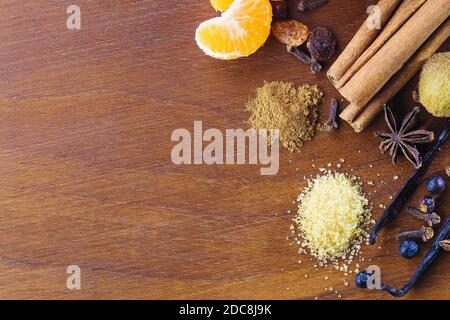 Nahaufnahme von aromatischen Weihnachtsgewürzen und Früchten für Glühwein oder heißen Gin auf Walnussholzplatte. Essen, Gewürze und Weihnachtskonzepte Stockfoto