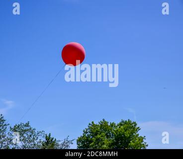 Einzelner roter Ballon schwebt die Luft gegen den blauen Himmel hinein Sommer Stockfoto