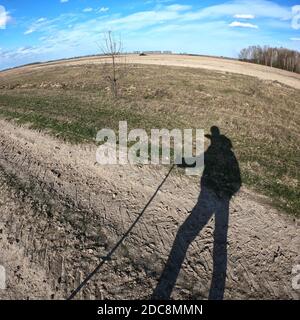 Schatten eines Reisenden mit einem Stock in der Hand. Landschaftsaufnahme mit Fischaugenobjektiv. Stockfoto