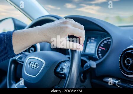 Selektiver Fokus auf die linke Hand einer kaukasischen Frau, die ihr Auto fährt. Stockfoto