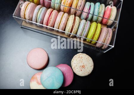 Französischer Makkaronenkuchen. Bunte Makronen auf dunklem Tisch und in Box mit Kopierraum Stockfoto