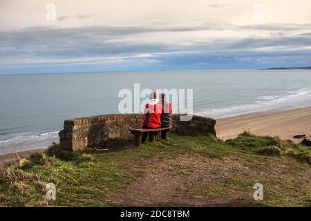 Romantische Szene mit einem verliebten Paar mit Blick auf den malerischen Blick auf St Cyrus Beach. Aberdeenshire, Schottland, Großbritannien. Stockfoto