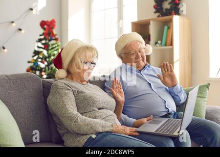 Ältere Paare, die einen Laptop verwenden, führen einen Videoanruf durch, um ihrer Familie zu Weihnachten zu gratulieren. Stockfoto