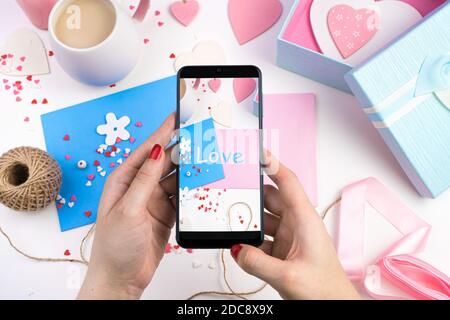 Weibliche Hände halten Telefon und Fotos von romantischen Hintergrund. Stockfoto