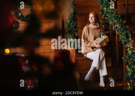 Breite Aufnahme von lächelnden rothaarigen Frau glücklich hält Geschenk-Box in der Hand für Weihnachten erhalten. Stockfoto