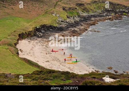 Eine Gruppe von Kanufahrern ruhen am Strand in Bread and Cheese Cove unterhalb der Tagesmarke auf der Insel St. Martin's in den Isles of Scilly, Cornwall.UK Stockfoto