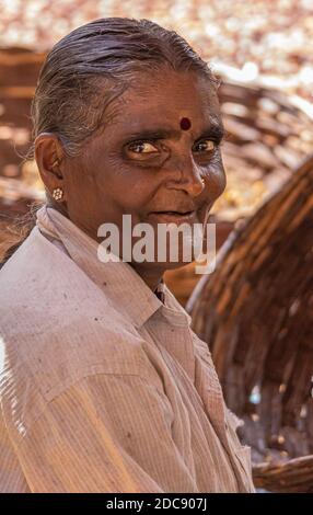 Chikkanayakanahalli, Karnataka, Indien - 3. November 2013: Nahaufnahme Porträt einer älteren zahnlosen lächelnden Frau mit beigefarbenem Hemd. Verblassenes Braun als Hintergrund Stockfoto