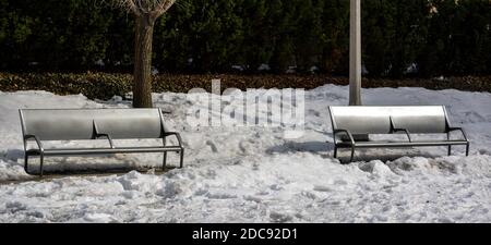 Leere moderne Parkbank im Winterschnee auf einem Sonniger Tag Stockfoto