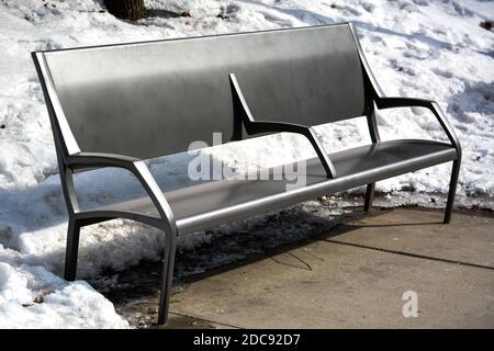 Leere moderne Parkbank im Winterschnee auf einem Sonniger Tag Stockfoto