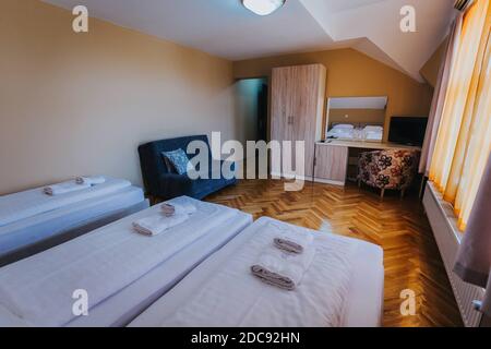 Ein Dreibettzimmer unter den Lichtern mit einem kleinen Tisch Und Vorhänge in einem Hotel Stockfoto