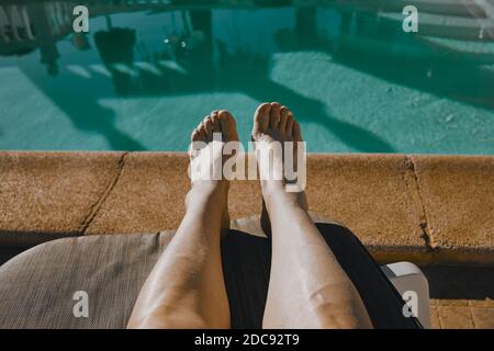 Frau Füße auf einem Sonnenstuhl vor einem Privater Pool Stockfoto