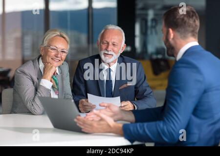 Positiv gealtertes Paar, das mit Versicherungsagent berät Stockfoto