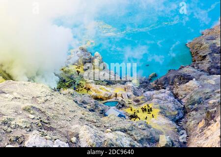 Vogelperspektive auf Schwefelminer, die am Turquoise Acid Crater Lake bei Kawah Ijen, Java, Indonesien, Asien arbeiten Stockfoto