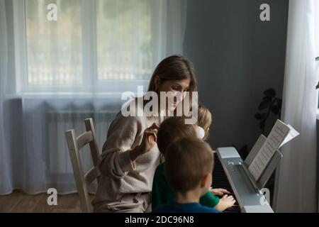 Kinder und Mama kommunizieren mit einem Synthesizer. Stockfoto