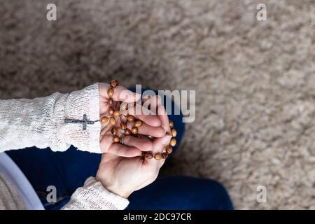 Frauen Hände halten Holz katholischen Rosenkranz im Gebet Stockfoto