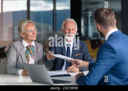 Positiv gealtertes Paar, das mit Versicherungsagent berät Stockfoto