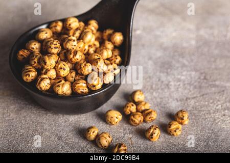 Geröstete, gelbe Kichererbsen in schwarzer Schale auf Steingrund (türkischer Name; Sari lebeblebi). Stockfoto