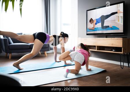 Frau Und Ihr Kind Mädchen Tun Online-Fitness-Übung In Virtuelle Klasse Stockfoto