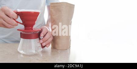 Stellen Sie das V60 neben dem Kaffeepaket auf dem Tisch ein. Männer Hand hält Glas Server. Pourover Stockfoto