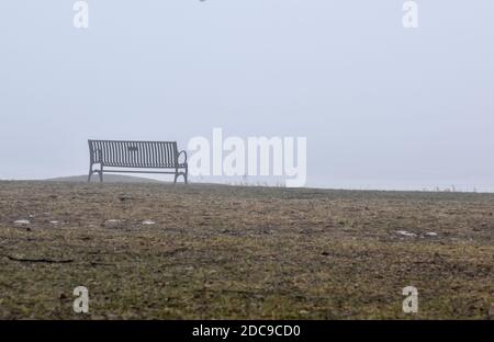 Leere Parkbank im Park an einem nebligen Morgen Stockfoto