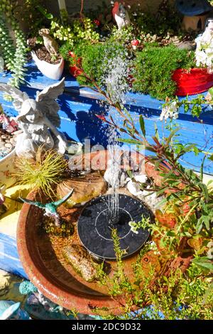 Ein kleiner solarbetriebener Wasserbrunnen ist Teil einer Besonderheit In einem Märchengarten Stockfoto