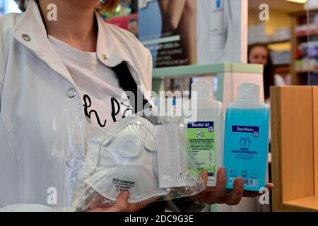 21.04.2020, Essen, Nordrhein-Westfalen, Deutschland - Angestellte einer Apotheke hält Desinfektionsmittel und eine Schutzmaske in der Hand. 0RL200421D004CAROEX. Stockfoto