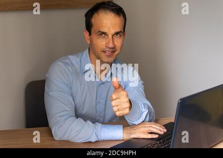 Mann in blauem Sozialhemd, der Daumen nach oben Zeichen macht. Stockfoto