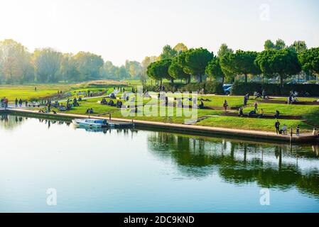 Menge von multiethnischen Menschen Chillen und entspannen in einem öffentlichen Park im Freien tragen warme Winterkleidung.Naturlandschaften mit grünen Bäumen und Gras. Stockfoto