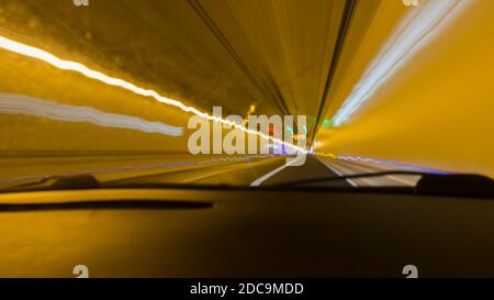 Blick aus einer Windschutzscheibe während der Fahrt durch Tunnel mit Verschwommenes Licht Stockfoto