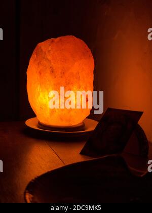 Orange beleuchtete Salzlampe auf Holzregal Stockfoto