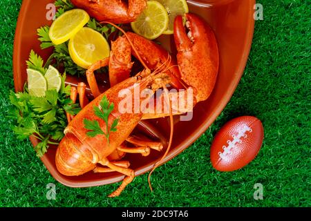 Bereit, roten Hummer mit Zitrone auf Fußball-Kugelplatte auf Gras Hintergrund zu essen. Stockfoto