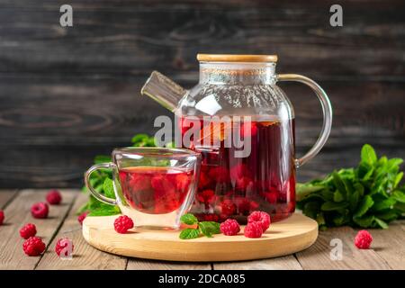 Kräutertee mit Beeren, Himbeeren, Minzblättern und Hibiskusblüten in Glas Teekanne und Tasse auf Holztisch Medizin für kaltes Vitamin Drink Rustikal Stockfoto