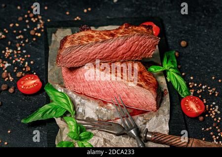 Seltenes Rindersteak. Gewürze und Kräuter auf dunklem Hintergrund. Saftiges und appetitliches Fleisch. Stockfoto