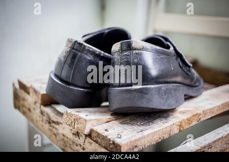 Alte schwarze Lederschuhe auf einer Palette Stockfoto