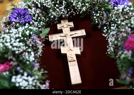 Hölzernes Kruzifix unter Blumen in der orthodoxen Kirche Stockfoto