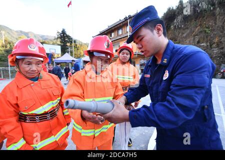 (201120) -- RONGSHUI, 20. November 2020 (Xinhua) -- Freiwillige nehmen am 19. November 2020 unter Anleitung professioneller Feuerwehrleute an einer Feuerübung im Dorf Wuying Teil, einem abgelegenen Dorf, das von der ethnischen Gruppe Miao an der Grenze zwischen der Autonomen Region Guangxi Zhuang im Süden Chinas und der Provinz Guizhou im Südwesten Chinas bewohnt wird. Da die Häuser mit dem lokalen Baustil im Dorf von einer bewaldeten Struktur unterstützt werden, wird ein Team von weiblichen Freiwilligen Feuerwehrleuten gebildet, um ihr Dorf zu schützen, da die meisten jungen und mittleren Alters Männer als Migranten ausziehen. (Xinhua/Huang Xiaobang) Stockfoto